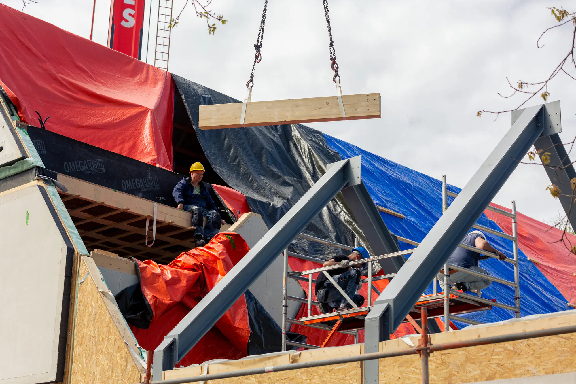 De kraan hijst een prefab wandelement op zijn plaats tijdens de montage